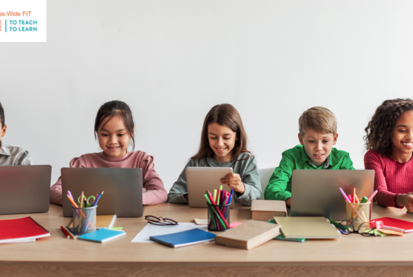 Elementary students sitting in a row working on laptops, demonstrating an established digital classroom routine for technology-based learning.