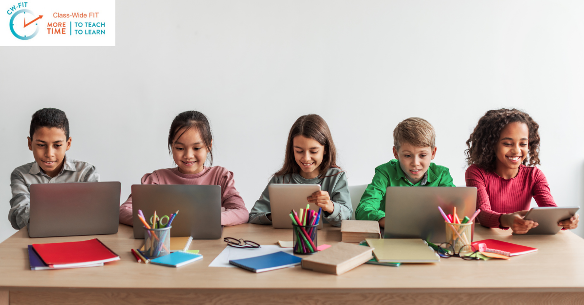 Elementary students sitting in a row working on laptops, demonstrating an established digital classroom routine for technology-based learning.