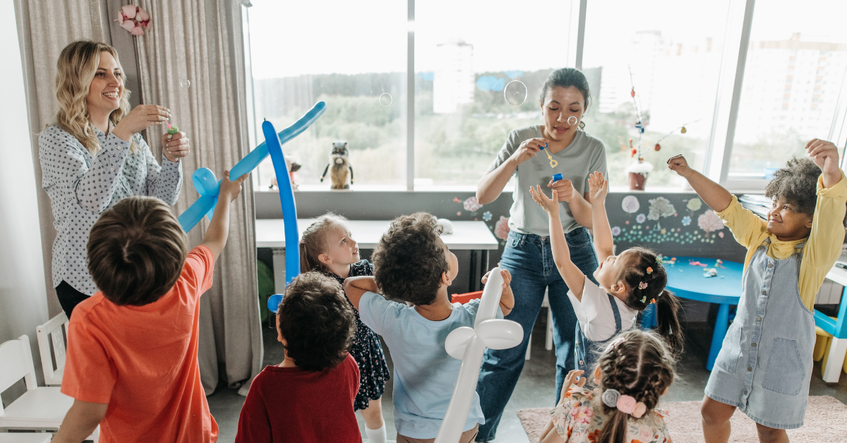 A group of happy elementary students enjoying a bubble party, demonstrating a low-cost Tier 1 PBIS incentive that promotes a positive school climate.